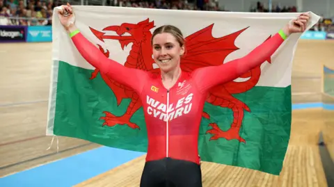 Getty Images Emma Finucane of Team Wales celebrates her victory in the Women's Sprint Finals by holding up a Welsh flag.