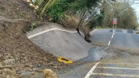 Lyneham Banks landslip causing the road to buckle and sit diagonally against the bank