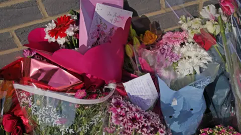 PA Media Brightly-coloured bunches of flowers, a Thinking of You card and a handwritten note