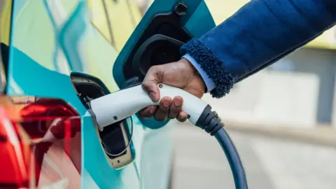 Person charging a blue electric car