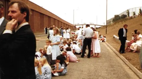 Trotman family Archive photo from 1989 of children sitting on a new road. Most are in school uniforms