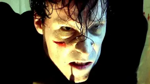 Nowhere Fast A scary-looking zombie in a dim light and a cut on his face. He is snarling