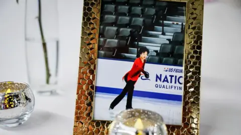 Getty Images Gold framed photo of Spencer Lane skating with red shirt and black pants next to candles