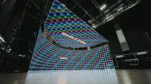 Patrick Hughes est un studio avec un écran vert composé d'une série de grandes grilles multicolores.
