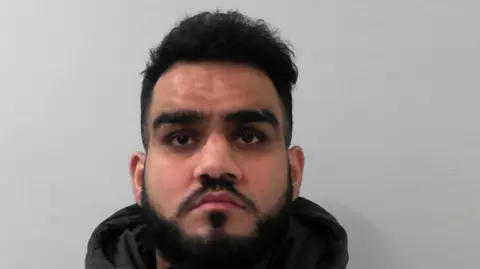 Mugshot of Mohammed Numaan, who has dark hair and a beard, looking straight at the camera.