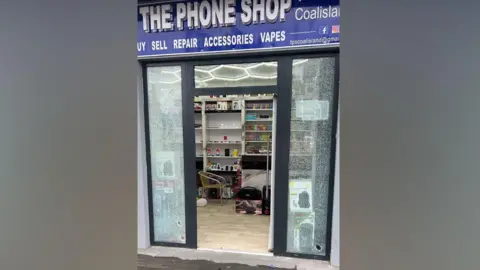 A shop front door with broken windows.