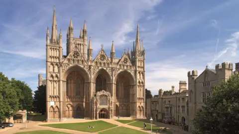 Peterborough Cathedral Main front of Peterborough Cathedral with a bright blue sky behind and green grassed area to the front