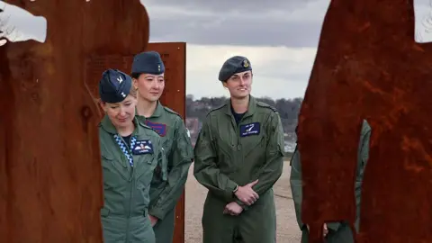 RAF Three women in RAF green jumpsuits surrounded by steel silhouettes of women in war