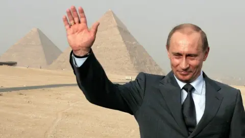 Getty Images Mr Putin waving his hand next to the pyramids in Egypt