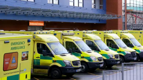 Half a dozen ambulances in fluorescent green and yellow livery, lined up outside Medway Maritime Hospital accident and emergency department 