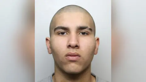 A police mugshot of Faaris Khalid - a teenager with a shaven head, thick eyebrows and a glib expression.