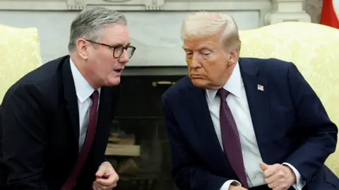 Sir Keir Starmer and Donald Trump sit beside each other in the Oval Office, with Trump leaning towards Starmer to hear what he is saying