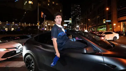 Getty Images Fans celebrate the Toronto Blue Jays' victory over the Seattle Mariners in Game 7 of the ALCS in Toronto. October 20, 2025