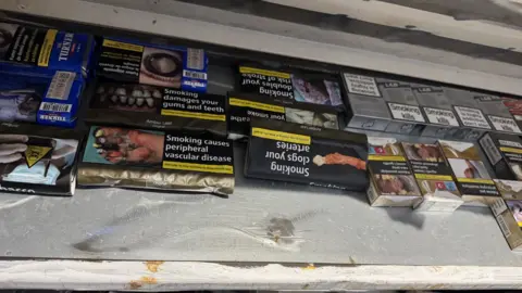 A variety of different packs of cigarettes on a shelf