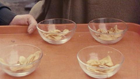 Four glass bowls containing crisps on an orange tray.