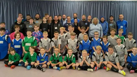 Berewood Image of children football plays and their football coaches, a mix of men and women.
