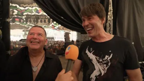 BBC Peter Cunnah and Brian Cox laughing back stage at Glastonbury 