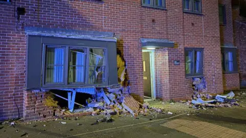 Nottinghamshire Police The front window of a block of flats in Nottingham has been damaged. Debris and bricks have been left on the floor. 