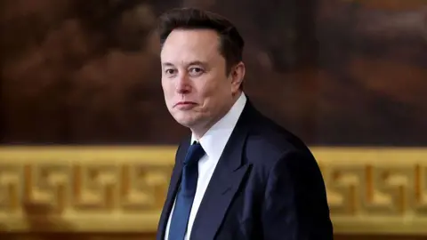 Elon Musk wearing a dark blue suit and tie, walking past a huge painting with a gold frame.
