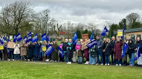 NASUWT Group of teachers and union members on the picket line waving navy blue flags and placards.