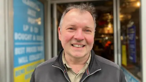 Ben Darnton, owner of Ben's Collector Records in Guildford, looks straight at the camera.