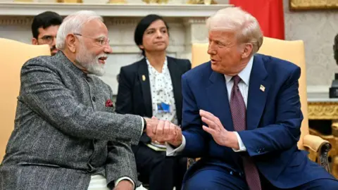 AFP via Getty Images US President Donald Trump - right, wearing a blue suit - shakes hands with Indian Prime Minister Narendra Modi in the Oval Office of the White House in Washington, DC