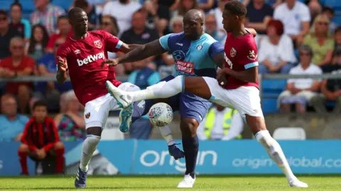 Getty Images Adebayo Akinfenwa of Wycombe Wanderers battles for the ball with Reece Oxford (R) and Pedro Obiang of West Ham