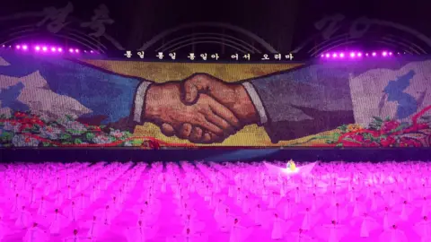 AFP A mural of shaking hands is displayed during a "mass games" gymnastic and artistic performance at the May Day Stadium in Pyongyang