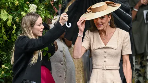 Reuters A woman is holding an umbrella above Kate Middleton.