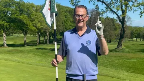 Kevin Popplewell A man stands on a golf course with a pole in his
