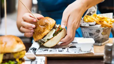 Getty Images Dining out on a burger and chips in a sit-down restaurant