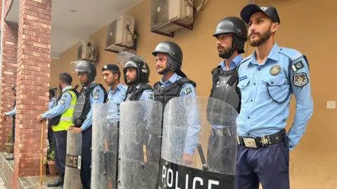 Police officers lined up outside Mr Khan's home