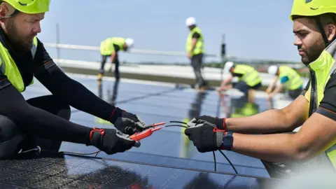 A stock image of people installing solar panels in the UK
