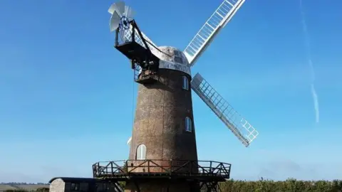 Wilton Windmill The red brick windmill with white sails under a bright blue sky