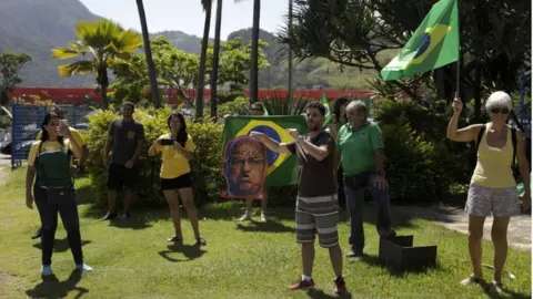 Reuters Demonstrators maintain social distance while protesting against Rio de Janeiro Governor Wilson Witzel's measures on the coronavirus disease (COVID-19) outbreak and in support of Brazil"s President Jair Bolsonaro, in Rio de Janeiro, Brazil, March 28, 2020.