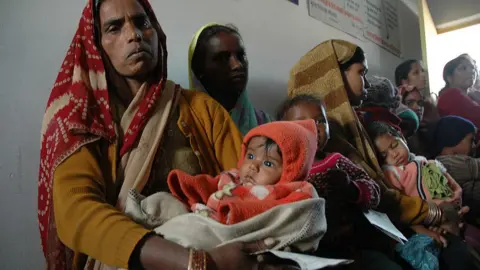 Getty Images Archive image showing Indian women waiting in line with children for vaccine clinic