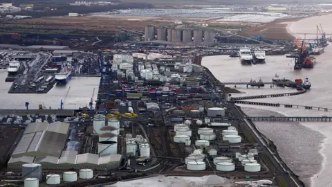 Aerial view of the port of Immingham there are a number of ships moored and many white gas storage tanks and shipping containers