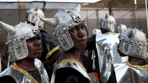 Reuters Two boys wear silver tops and silver helmets with horns on them.