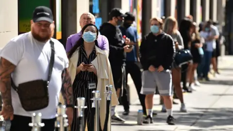 AFP People queue outside a shop in London