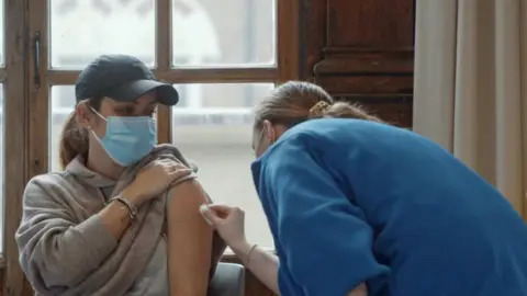 DHSC Woman being vaccinated in government advert, "Every vaccination gives us hope"