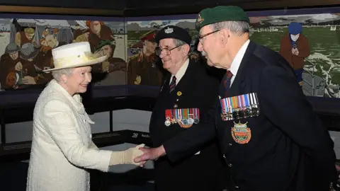 Getty Images/David Parker Queen Elizabeth II, dressed in a cream hat and jacket, meets D-Day veterans Frank Rosier and Eddie Wallace - who are dressed in military ceremonial dress - next to the the Overlord Embroidery aduring her visit to the D-Day museum as it marks its 25th anniversary on April 30, 2009 in Portsmouth.