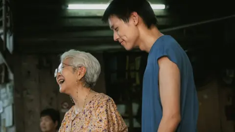 M laughing with his grandmother in a scene in the film