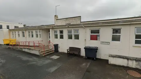 Google The Donbank Ward. A white single-storey building. There are multiple windows, and a small set of stairs and ramp to the main door. 