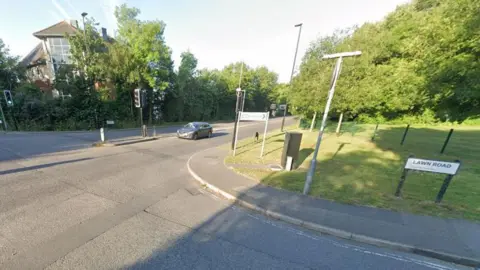 Road junction with traffic lights and trees along the sides.