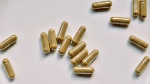 Getty Images green tea supplement capsules scattered on a table