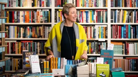 Emma Corfield-Walters Emma Corfield-Walters standing in from of shelves full of books