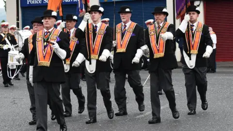 Pacemaker A group of Orangemen are marching wearing orange sashes, white gloves and bowler hats