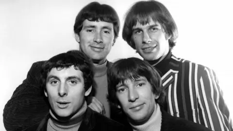 A black and white image of the Troggs - Reg Presley, Chris Britton wearing pinstripes, Pete Staples and Ronnie Bond photographed backstage at Top Of The Pops.