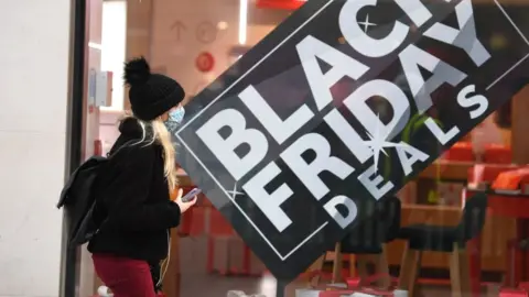 Getty Images Woman walks past Black Friday promotion sign