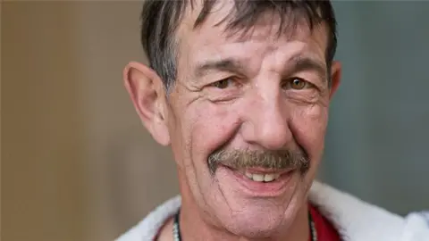 Supplied A close-up images of Ian Coates. He is wearing a grey hoody and has a lanyard around his neck. 